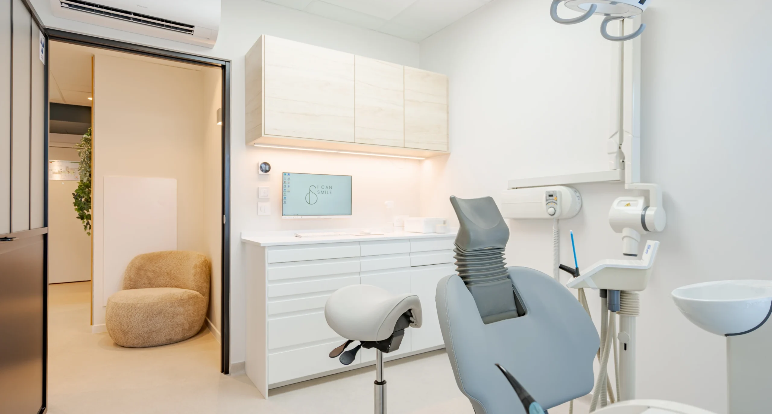 Salle de soins vue depuis le couloir, fauteuil dentaire au centre